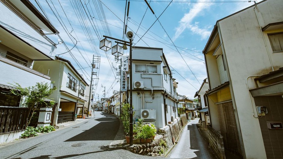 Explore a picturesque narrow street lined with traditional houses under a clear blue sky.
